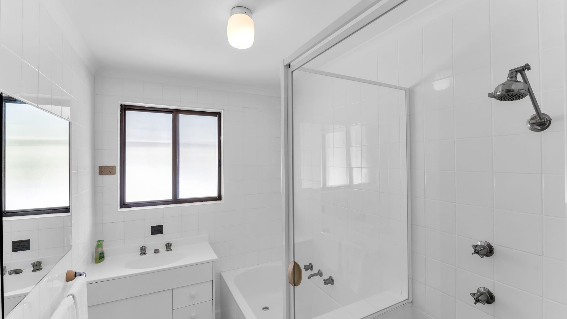 A modern bathroom with a glass shower enclosure, a bathtub, and a vanity with a mirror.