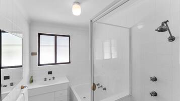 A modern bathroom with a glass shower enclosure, a bathtub, and a vanity with a mirror.