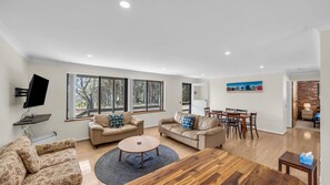 A modern living room with two sofas, a coffee table, and a TV mounted on the wall.