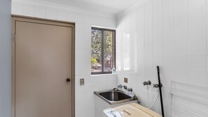 A bathroom with white tiles, a window, a sink, and a door.