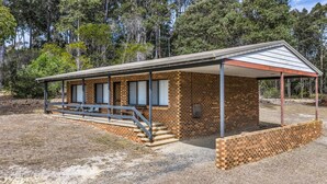 Un pequeño edificio de ladrillo con un porche cubierto, una escalera que conduce a la entrada y una banca afuera.