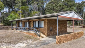 A small brick building with a covered porch, a set of steps leading to the entrance, and a bench outside. - Cuttagee Beach Cottage 3 - Tathra Bermagui Rd 3521 (BARRAGGA BAY)