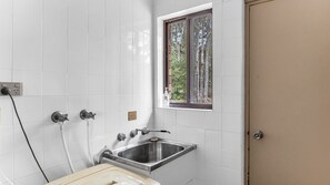 A bathroom with white tiles, a window, a sink, and a toilet.