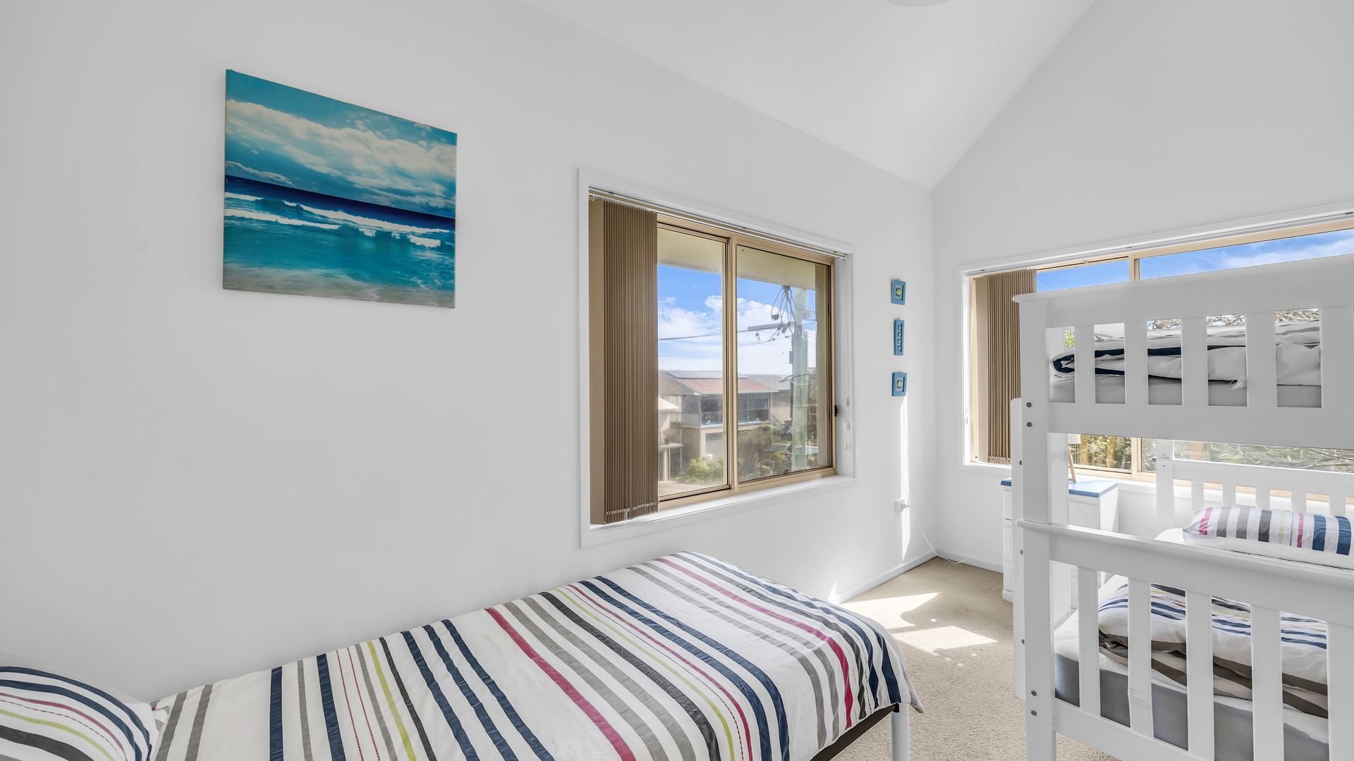A room with a bed, a window with a view, and a crib.
