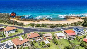 A coastal residential area with houses, a road, and a beach.