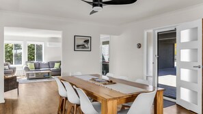 Ein modernes Interieur mit Essbereich, einer Sofagarnitur und Blick durch eine offene Tür.
