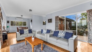 A modern living room with a sofa set, a coffee table, and a dining area with chairs and a table.