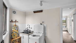 Een kleine keuken met een wasmachine, een spoelbak en een droogrek.
