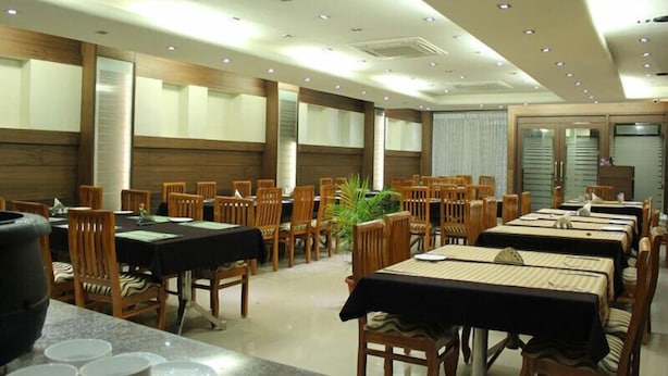 A dining area with multiple tables and chairs, arranged in rows. - Moskva Hotel (Madurai)