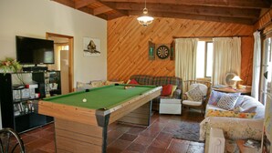 Una sala de estar acogedora con mesa de billar, televisor y dardos.