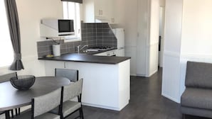 Une cuisine moderne dotée d’un îlot central, de meubles blancs et d’un plancher en bois foncé.