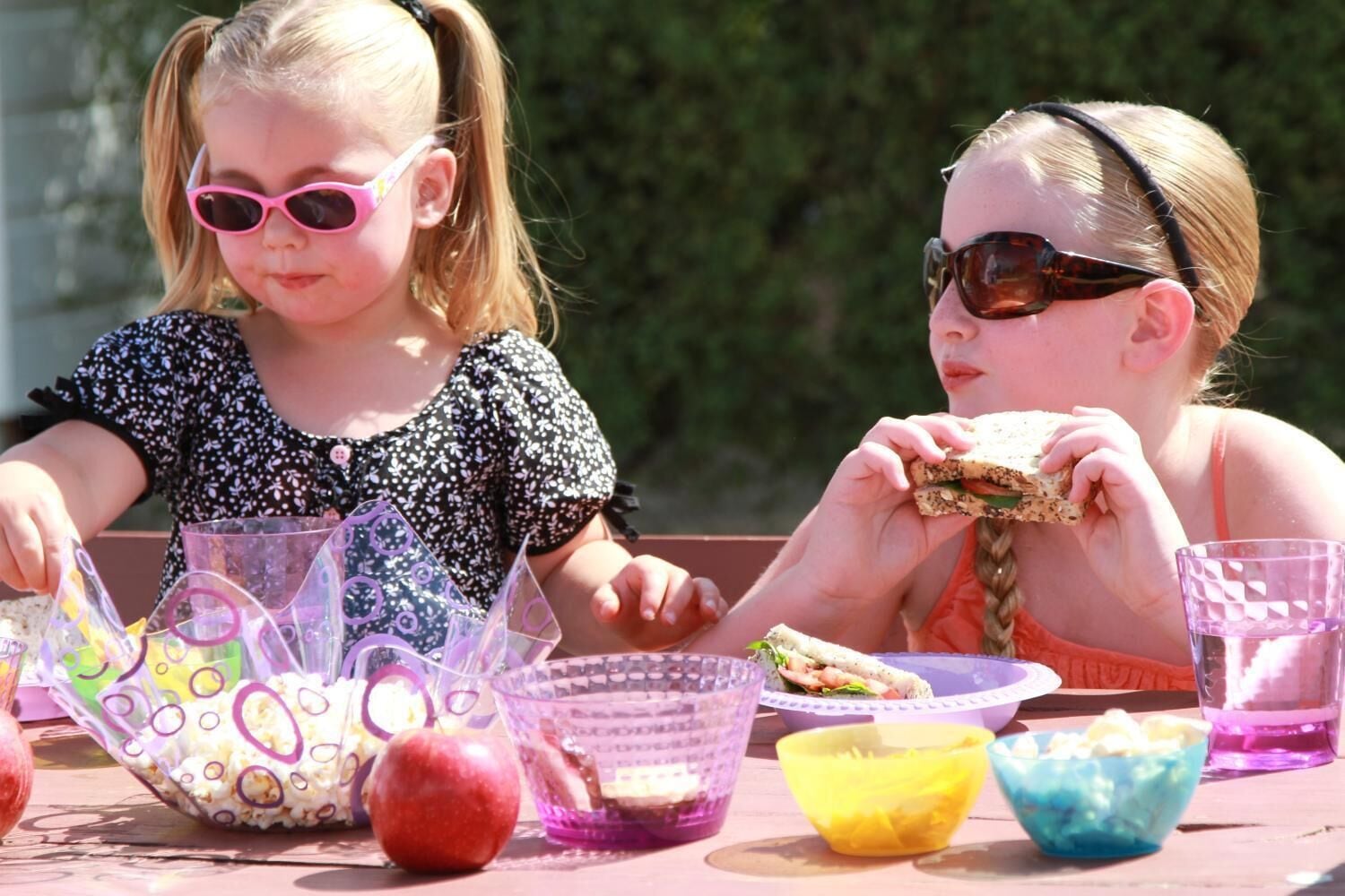 Two children at a table with food items and drinks.