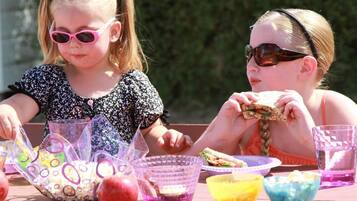 Two children at a table with food items and drinks.