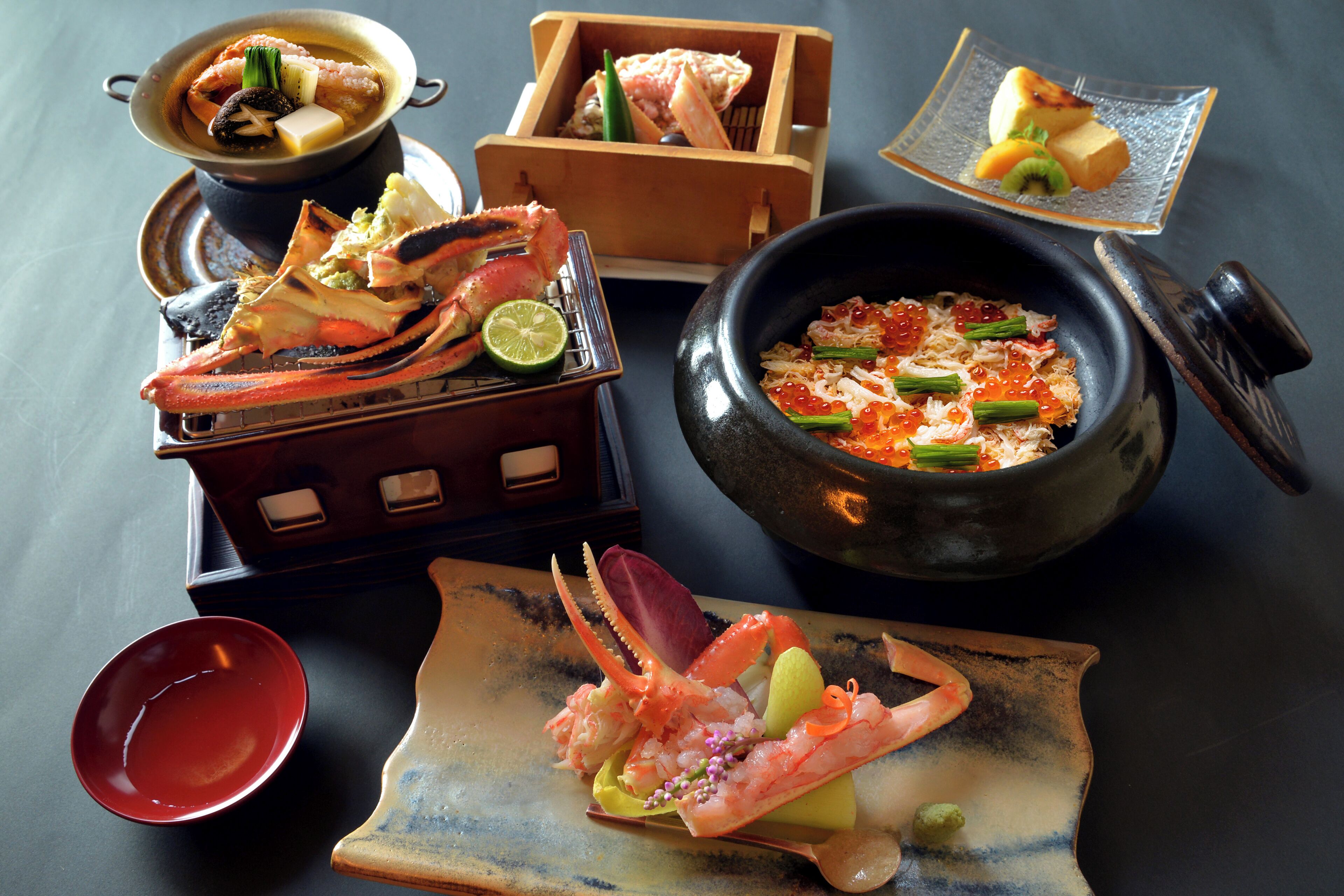 A variety of seafood dishes, including a bowl of soup, a plate with shrimp and vegetables, and a dish with crab.