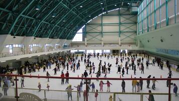 An indoor ice skating rink with a high ceiling and multiple levels.