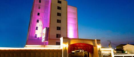 Un hotel con un letrero llamativo, fachada de ladrillo y toldo rojo.