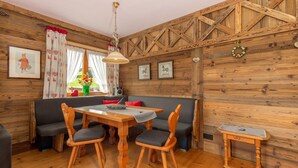 A wooden interior with a wooden table, two chairs, a bench, and a small side table. - Ferienwohnung (09) im Birkenhof (Reit im Winkl)
