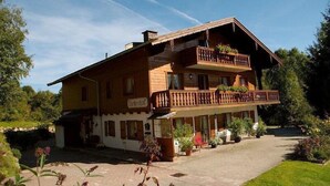 A traditional wooden chalet with a balcony, a sign reading "Gästehaus," and a paved driveway. - Ferienwohnung (09) im Birkenhof (Reit im Winkl)