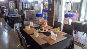 Un restaurant amb parets de maó, zona de bar i taules preparades per sopar.