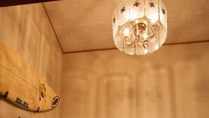 Una habitación con un barril de madera, una planta en maceta, una tabla de surf y un candelabro.