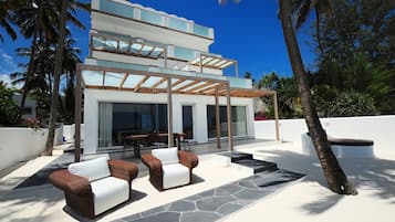 Relax on the two-tiered balcony overlooking a lush garden, with comfortable seating and a dining table.