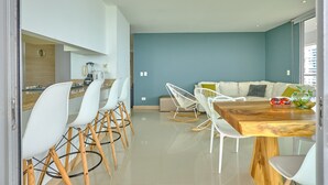 Une cuisine moderne avec des chaises blanches, une table à manger en bois et un mur bleu.