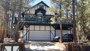 A two-story house with a balcony, garage, and surrounding trees.