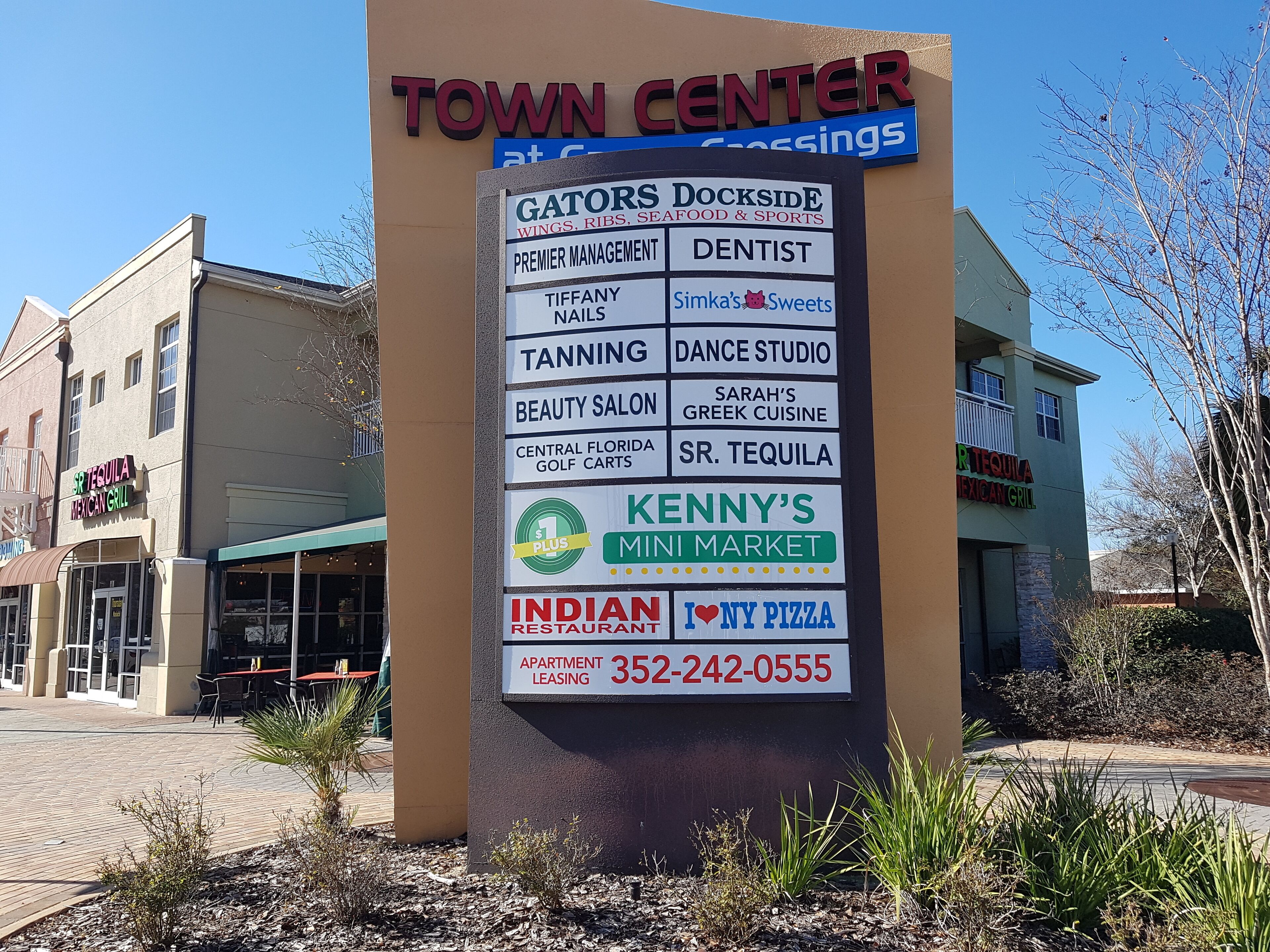 A signboard listing various businesses and services at Town Center, including a dentist, nails, tanning, and a mini market.
