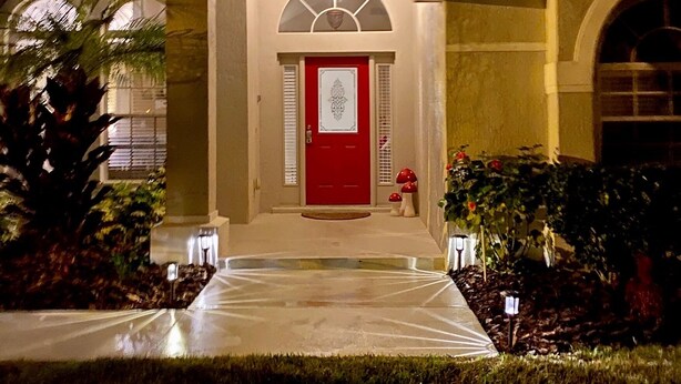 Une maison avec une porte rouge, un porche et un luminaire au-dessus de la porte.