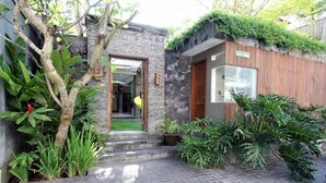 A modern house with a stone facade, a wooden door, and a paved entrance. - Villa Anya Seminyak (Seminyak)