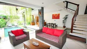 A modern living room with a pool, wicker furniture, and a staircase. - Villa Anya Seminyak (Seminyak)