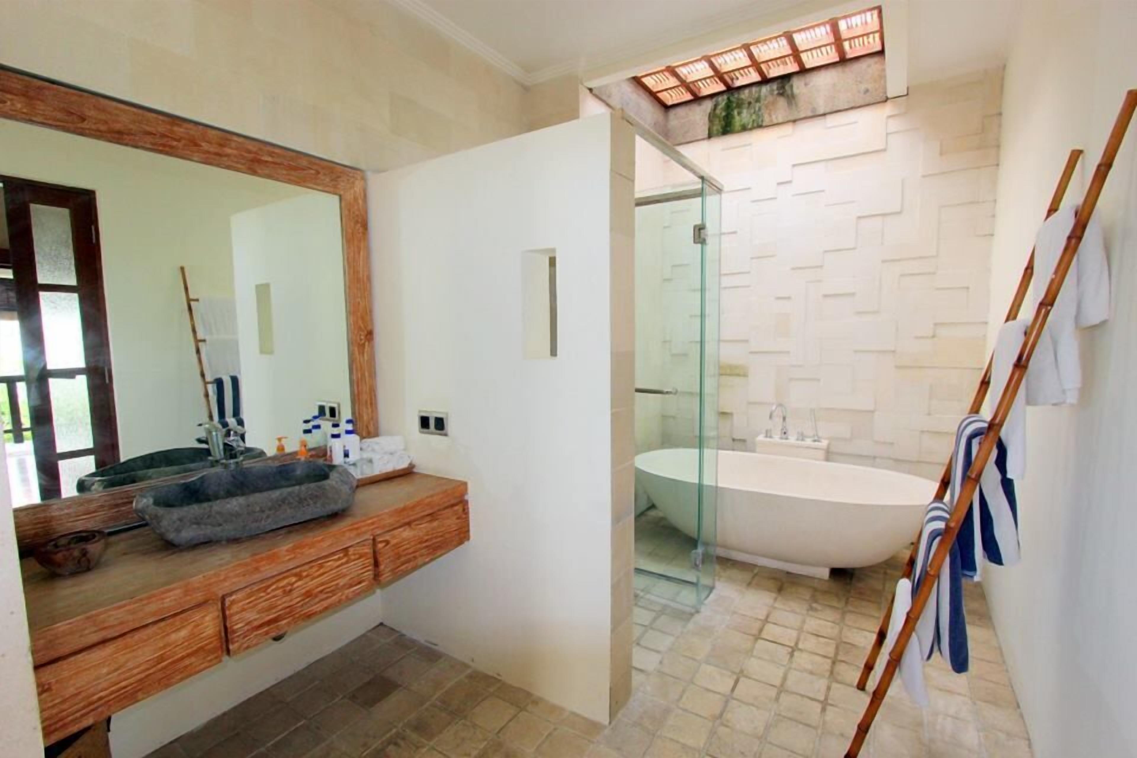 Un baño moderno con un espejo grande, una bañera independiente y una ducha con cerramiento de vidrio.