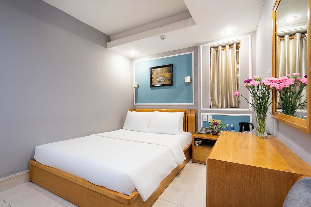 A neatly made bed with white linens in a hotel room.