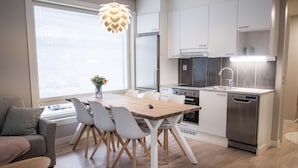 Una cocina moderna con armarios blancos, una mesa de comedor de madera y un lavavajillas empotrado.