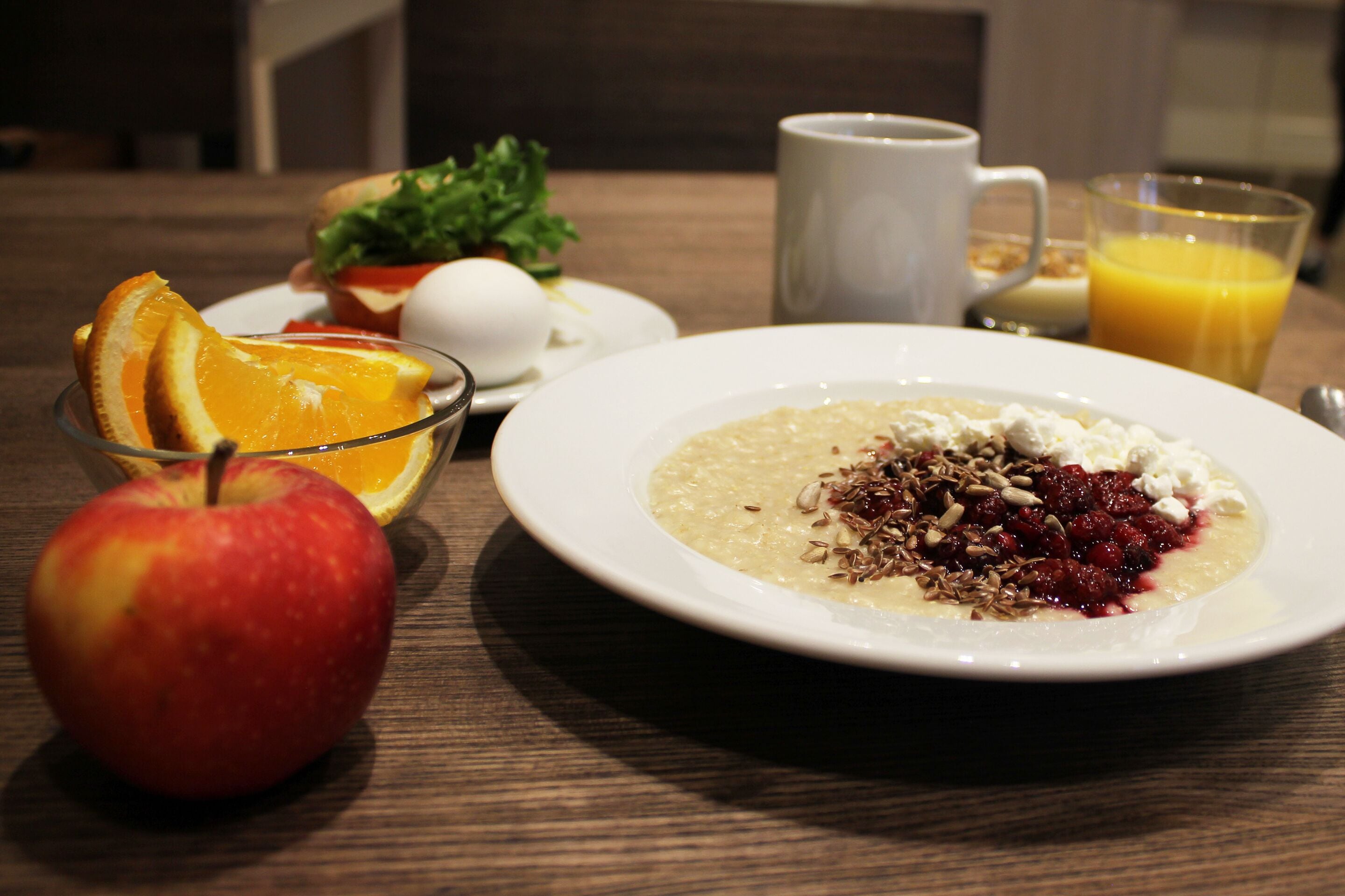 A breakfast setting with a plate of oatmeal, a bowl of fruit, a glass of orange juice, and a cup of coffee.