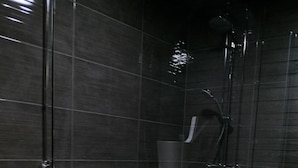 Un baño moderno con cabina de ducha de vidrio, un tocador blanco con lavamanos y un recipiente metálico con hielo.