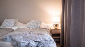 Cama bem arrumada com travesseiro fofo e luminária em uma mesa de cabeceira.