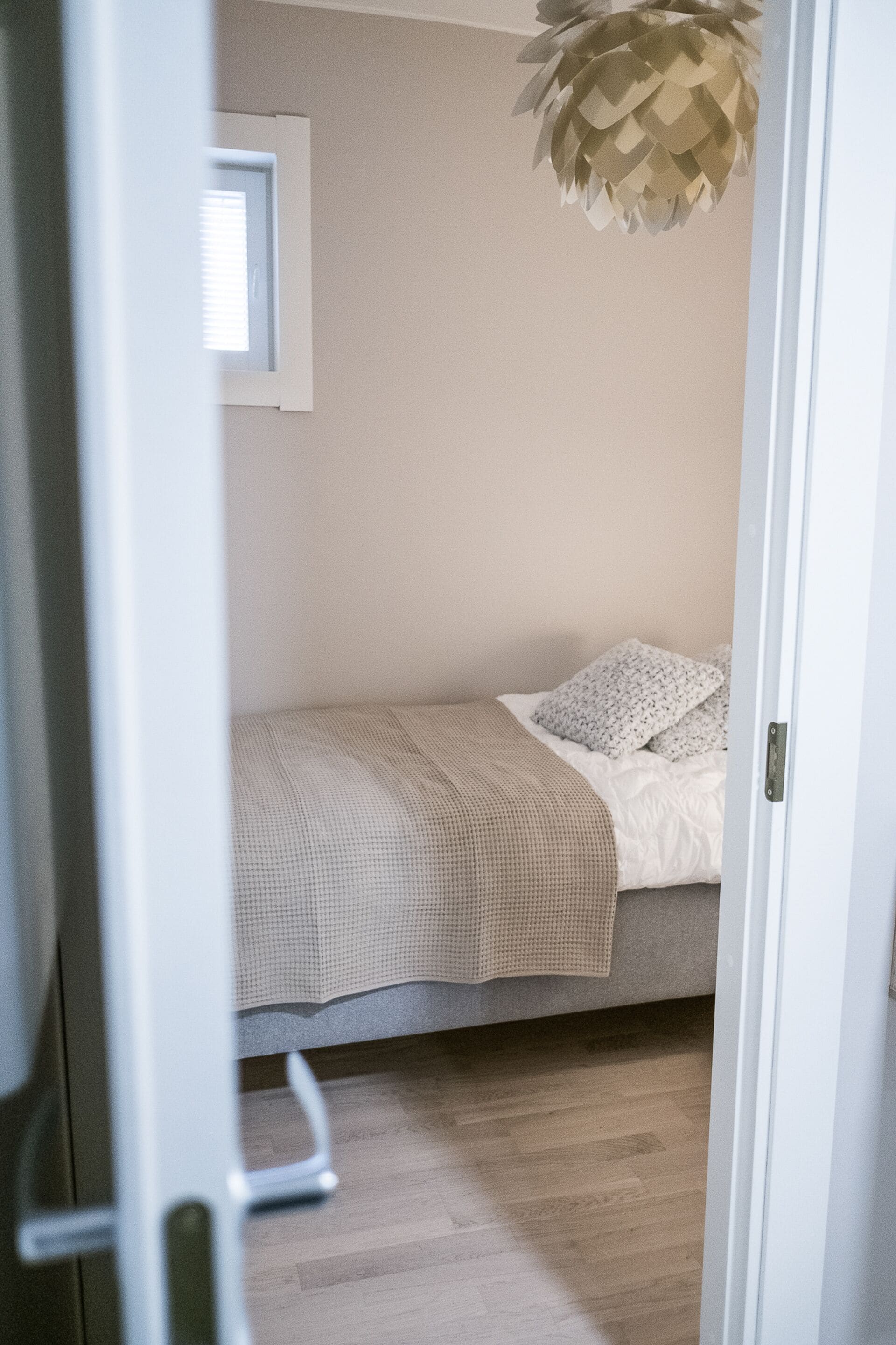 Un dormitorio con una cama, una ventana y una lámpara colgante.