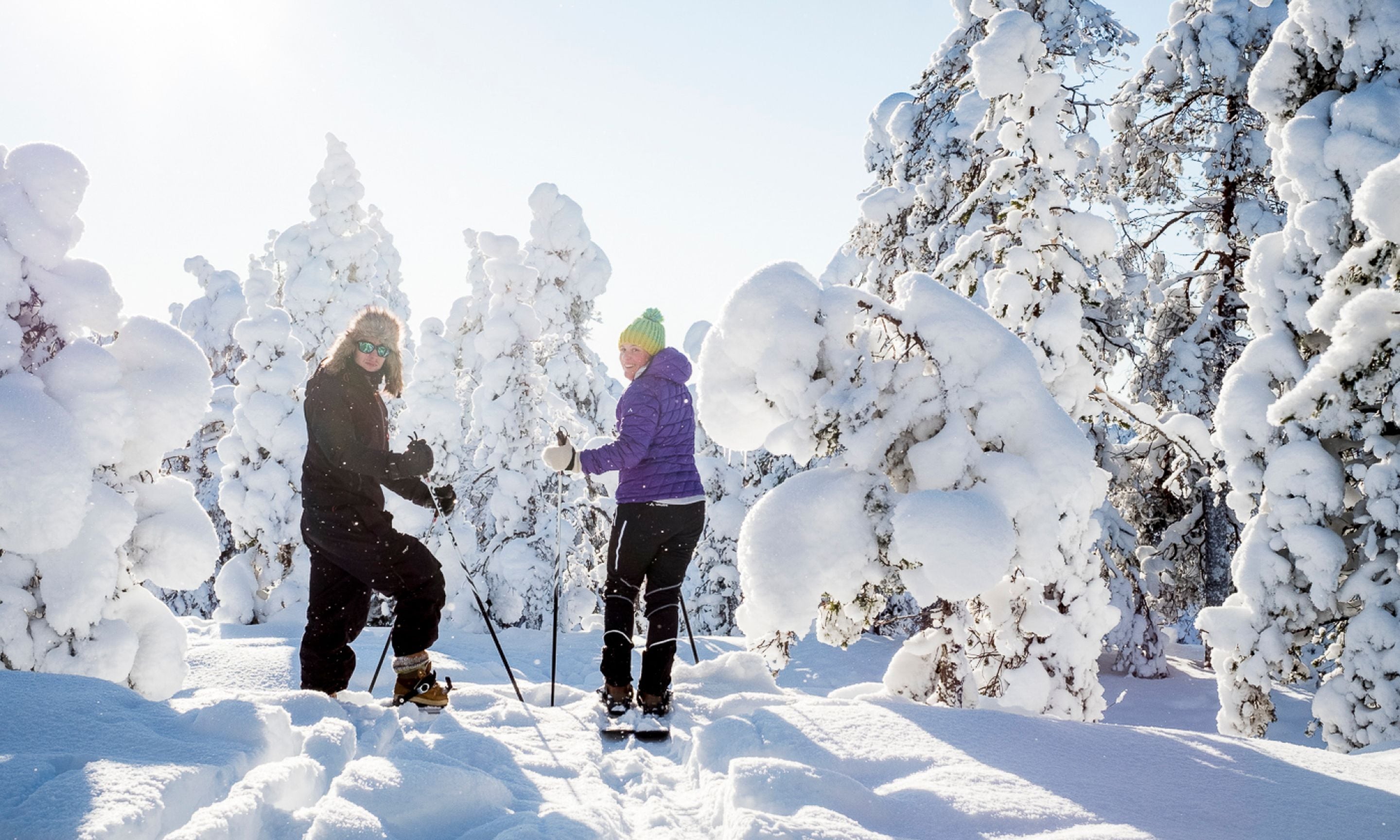 Un paysage enneigé où l’on voit deux personnes faire du ski.