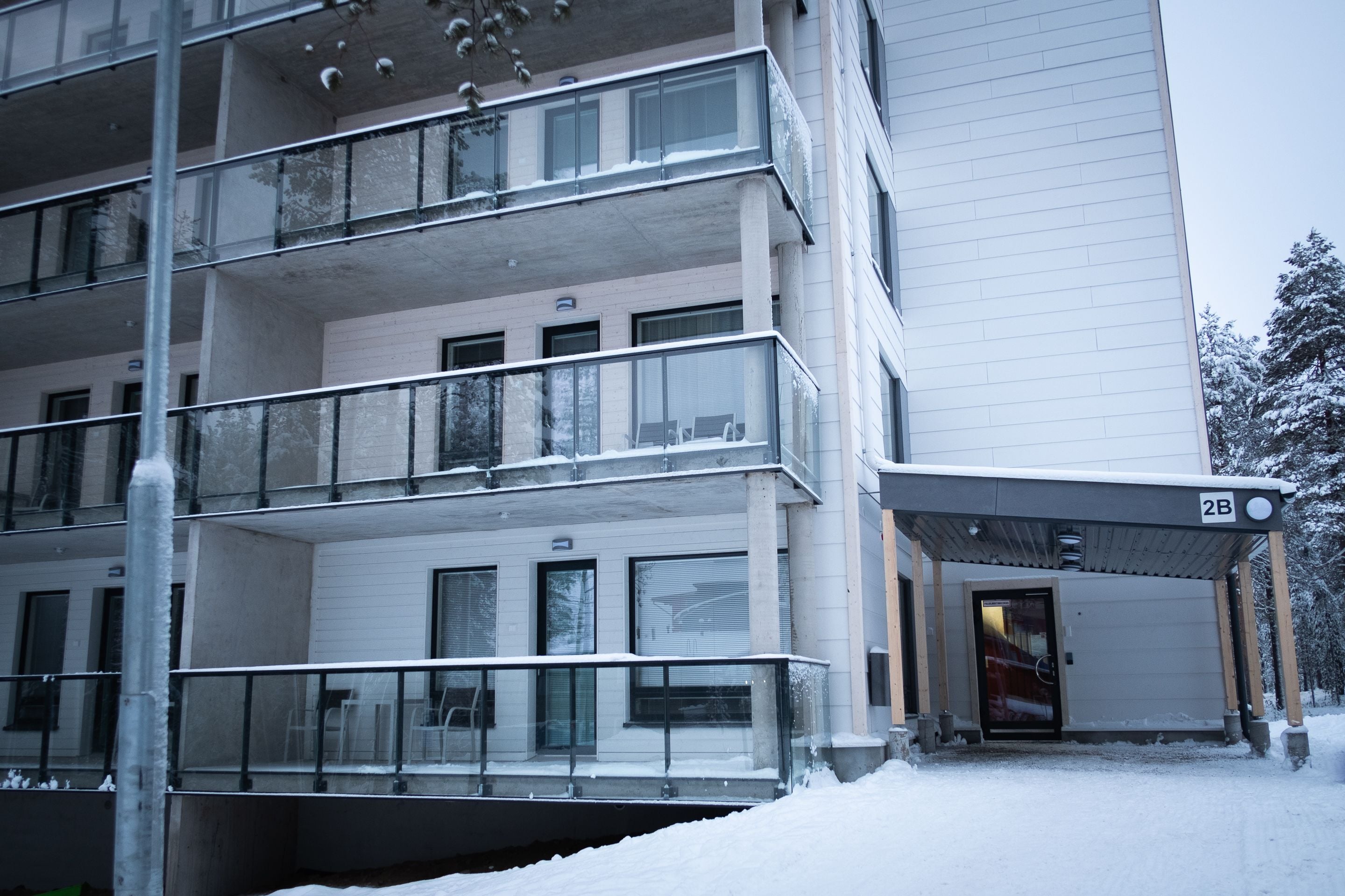 Un edificio de varios pisos con un vestíbulo cubierto, balcones y un suelo cubierto de nieve.