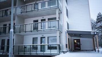 Un edificio de varios pisos con un vestíbulo cubierto, balcones y un suelo cubierto de nieve.