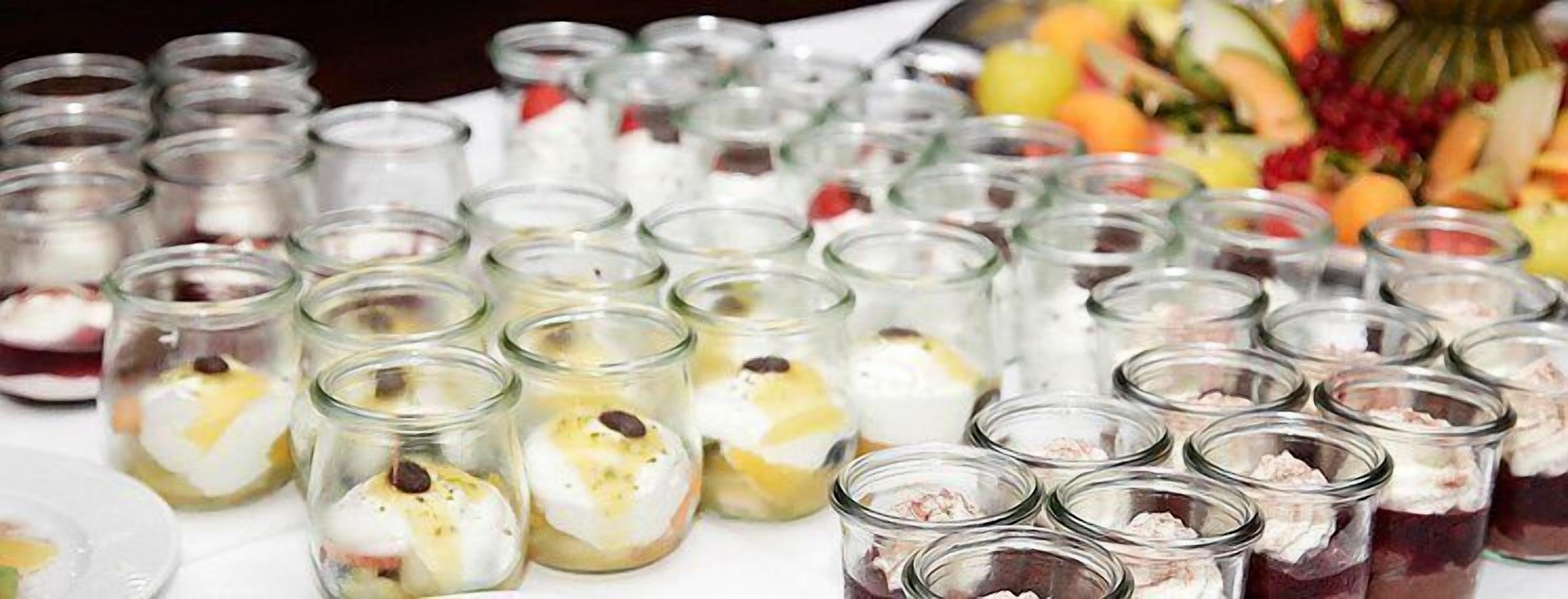 A table with multiple glass jars containing layered desserts.