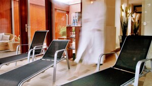 A hotel lobby with lounge chairs, a wooden door, and a brick wall. - Hotel Landhaus Pollmeyer (Friesoythe)