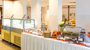 Uma mesa de buffet com estação de serviço, variedade de frutas e estação de café.