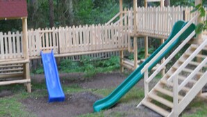 A playground with a slide and climbing structures. - Pensiunea Cabana Sestina (Lunca Bradului)