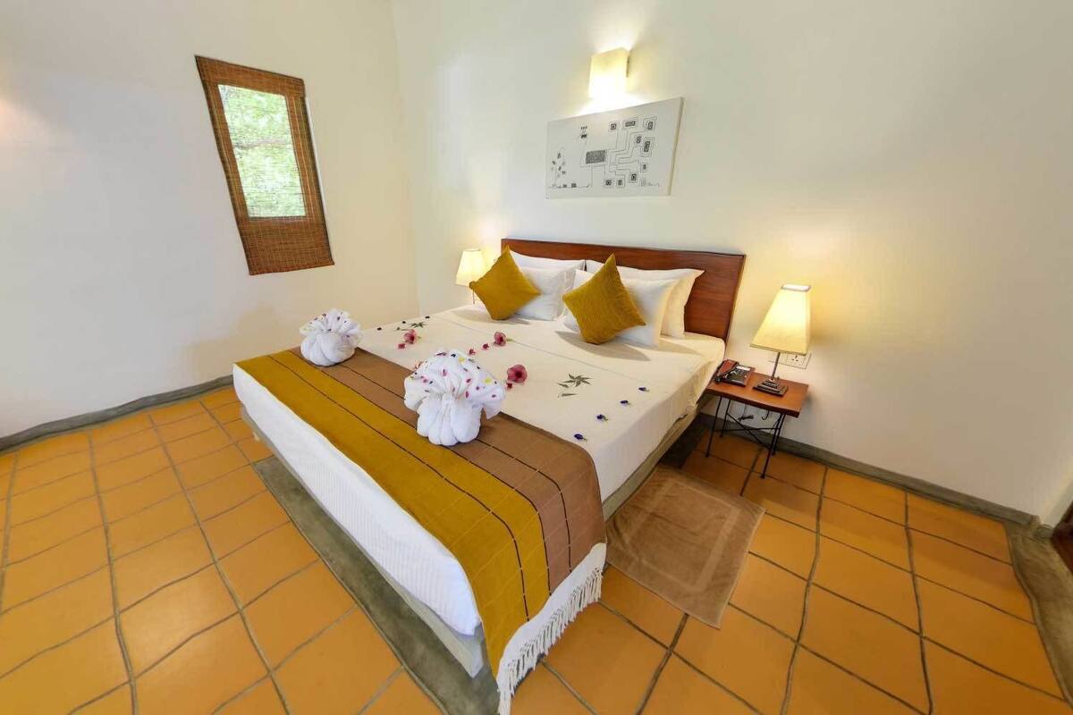Quarto de hotel com cama, mesa de cabeceira, mapa na parede e janela com persianas.