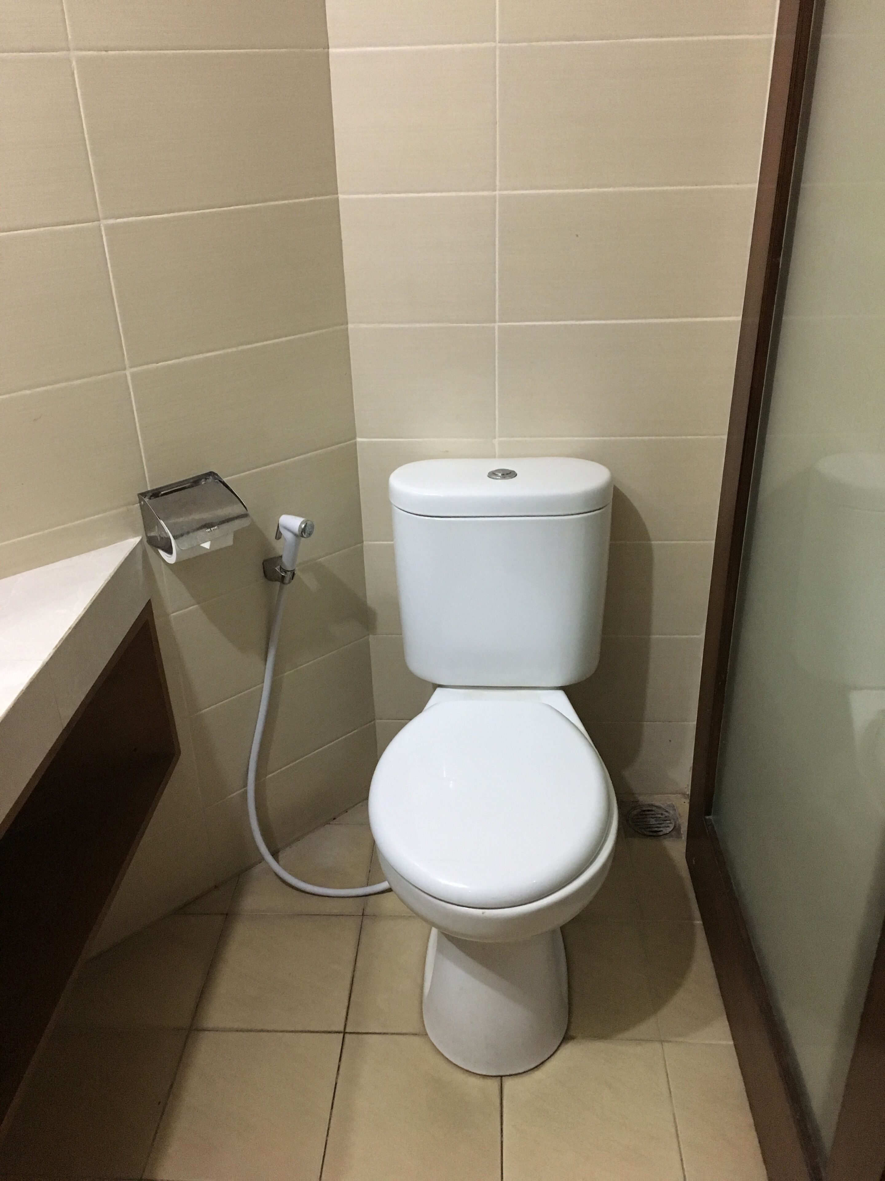 Un baño pequeño y limpio con inodoro blanco, un dispensador de toallas de papel y una zona de ducha.