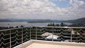 A balcony with a metal railing overlooking a body of water and distant hills. - Hotel Hilltop International (Port Blair)
