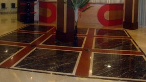 A spacious lobby with a marble floor, large pillars, and a central plant. - Hotel Hilltop International (Port Blair)