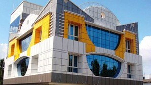A modern building with a unique architectural design, featuring large windows and a combination of yellow and grey colors. - Hotel Hilltop International (Port Blair)